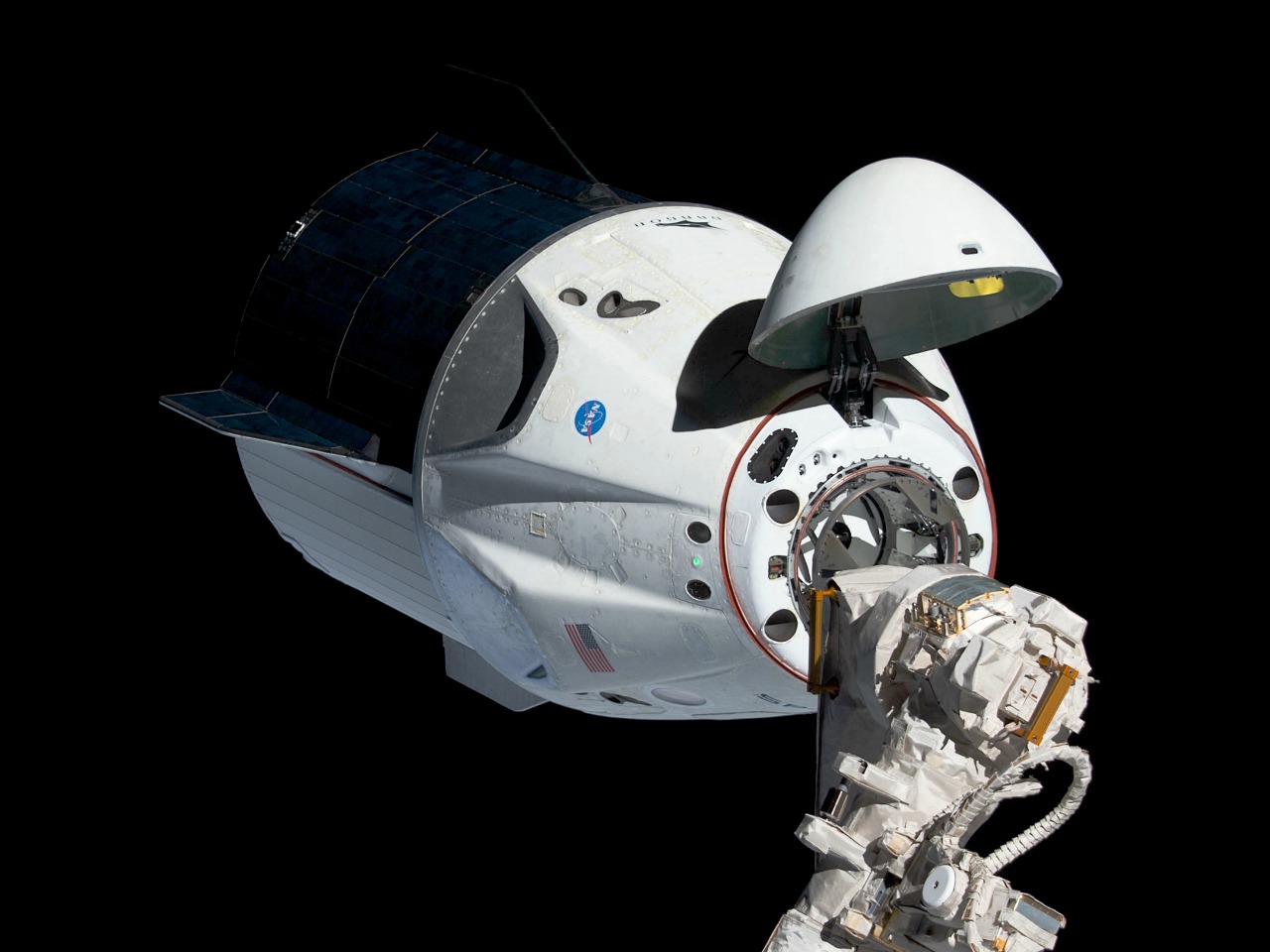 The uncrewed SpaceX Crew Dragon spacecraft is the first Commercial Crew vehicle to visit the International Space Station. Here it is pictured with its nose cone open revealing its docking mechanism while approaching the station's Harmony module. The Crew Dragon would automatically dock moments later to the international docking adapter attached to the forward end of Harmony. (cropped and brightened from the original)