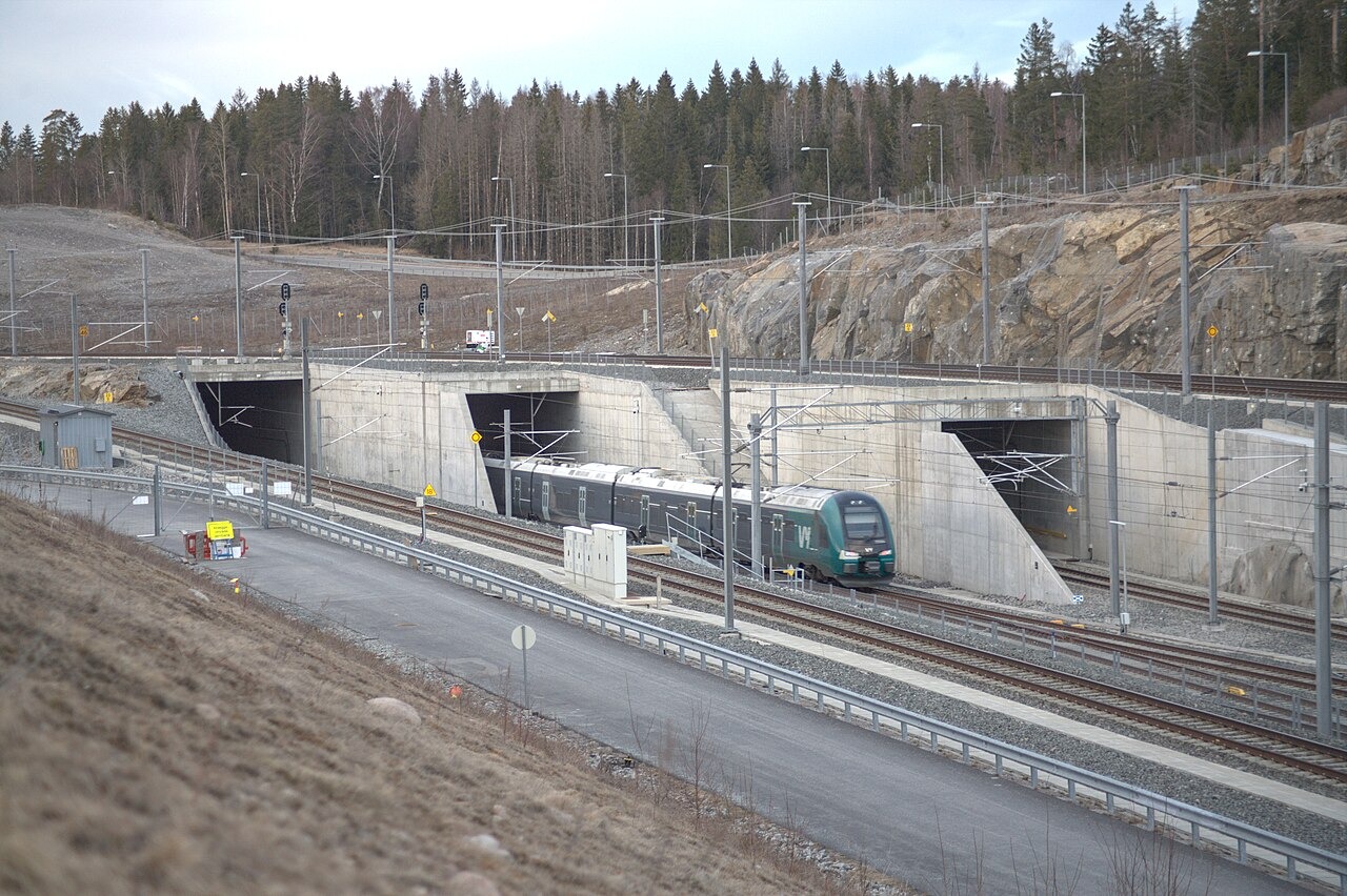 A train class 75 enters the southern portal of the Blix Tunnel on the Follo Line at Ski. The two tunnels on the left is the Blix Tunnel, where most of the Follo Line runs in. The tunnel on the far-right is the Roås Tunnel, where the track leads to the Østfold Line.