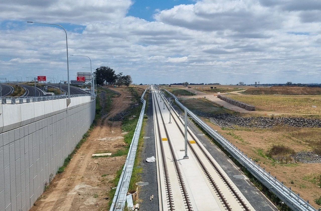 A section of recently constructed railway track for en:Sydney Metro Western Sydney Airport, with the en:M12 Motorway (Sydney) visible on the left.